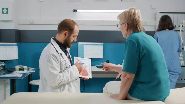 Health specialist showing cardiology illustration on digital tablet