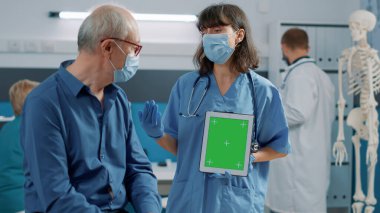 Yeşil ekranlı tableti dikey olarak tutan asistan