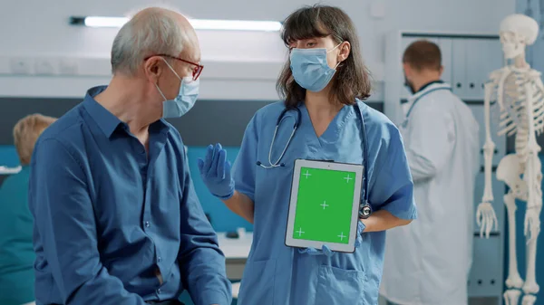 Yeşil ekranlı tableti dikey olarak tutan asistan