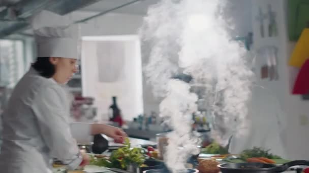 Mulher usando frigideira para cozinhar legumes no fogão de cozinha — Vídeo de Stock