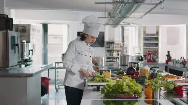 Retrato de cozinheira feminina cortando aipo verde na cozinha gourmet — Vídeo de Stock