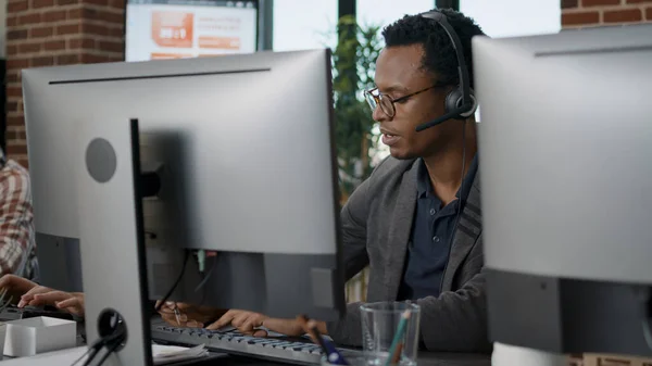 Afrika kökenli Amerikalı çalışan müşteri hizmetlerinde kulaklık kullanıyor. — Stok fotoğraf