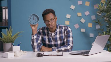 Saati gösteren ve teslim tarihinden dolayı hayal kırıklığına uğrayan bir adam.