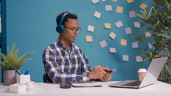 Uomo afroamericano utilizzando joystick sul computer portatile per giocare ai videogiochi — Foto Stock