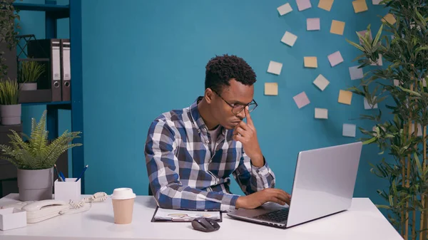 Adulto afroamericano che lavora su laptop con file grafici — Foto Stock