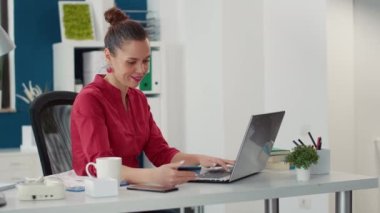 Ofis çalışanı laptopta kredi kartıyla ödeme yapıyor.