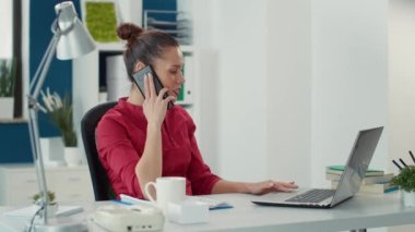 İş kadını proje yöneticisiyle konuşmak için akıllı telefon kullanıyor