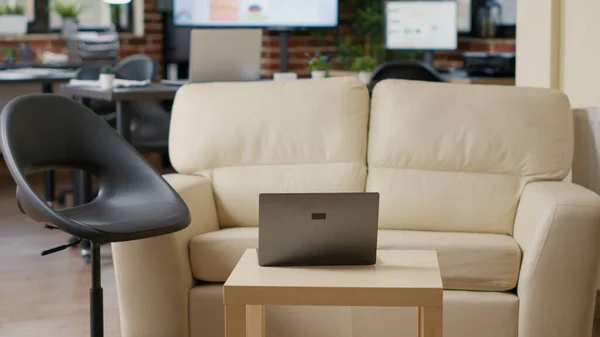 Empty startup office with couch and laptop computer — Stock Photo, Image