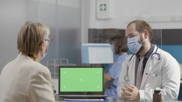 Senior kvinna och läkare tittar på greenscreen på bärbar dator — Stockfoto