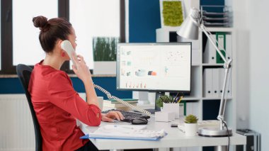 Ofis sekreteri iş hakkında konuşmak için sabit telefonu kullanıyor.