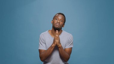 Umut dolu adam ellerini kameranın önüne koyarak dua ediyor.