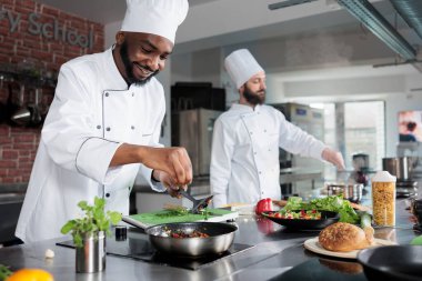 Afro-amerikan usta aşçı büyük bıçağı kullanarak organik otları ve sebzeleri güveç olarak kesiyor..