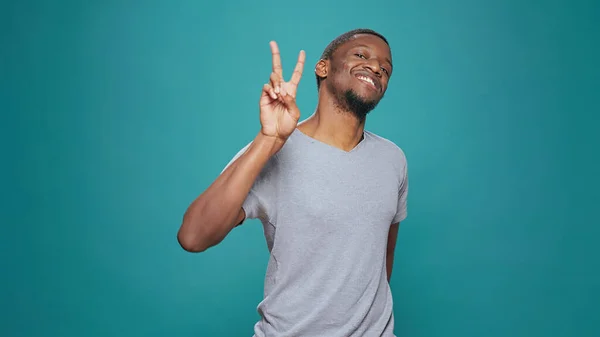 Positive model showing peace sign with hands on camera — Stock Photo, Image