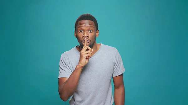 Portrait of secretive man doing hush sign in front of camera — ストック写真