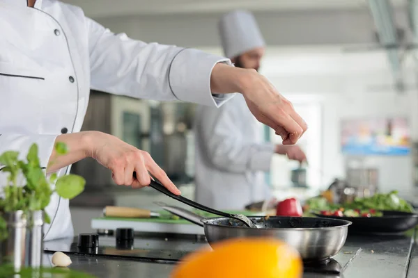 Meisterkoch in der professionellen Küche würzt Gemüse Gourmet-Gericht Eintopf mit frischen Bio-Kräutern und Gewürzen. lizenzfreie Stockbilder