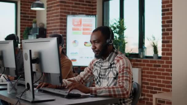 Hombre joven usando auriculares en el centro de llamadas para ayudar a la gente — Vídeos de Stock