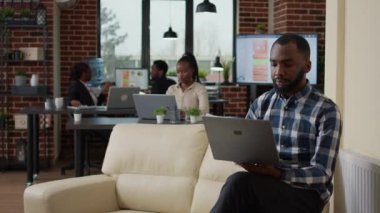 Afrikalı Amerikalı adam finansal istatistik oluşturmak için dizüstü bilgisayar kullanıyor