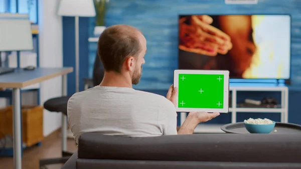 男子手持绿色屏幕数码平板电脑观看社交媒体视频内容的背景图 — 图库照片