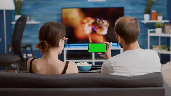 Статический кадр со штативом, на котором мужчина держит смартфон с зеленым экраном и смотрит онлайн-видео с подругой — стоковое фото
