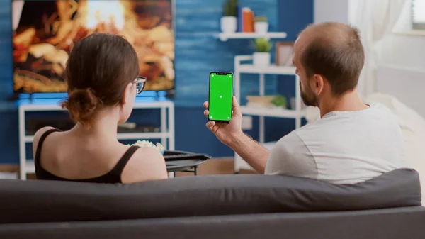 Coppia tenendo smartphone verticale con schermo verde parlando di contenuti di social media — Foto Stock