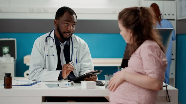 General practitioner using digital tablet at consultation with future mother