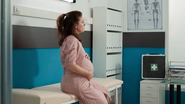Retrato de mulher jovem com barriga de gravidez sentado em consultório médico — Fotografia de Stock