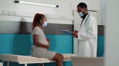 Doktor hamile kadının muayenesinde not alıyor.