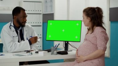 Masasında yeşil ekran olan bilgisayar kullanan bir tıp uzmanı.