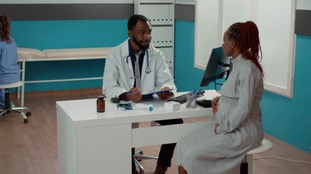 Amerykański lekarz i pacjent oczekujący spotkania dziecka w gabinecie — Wideo stockowe