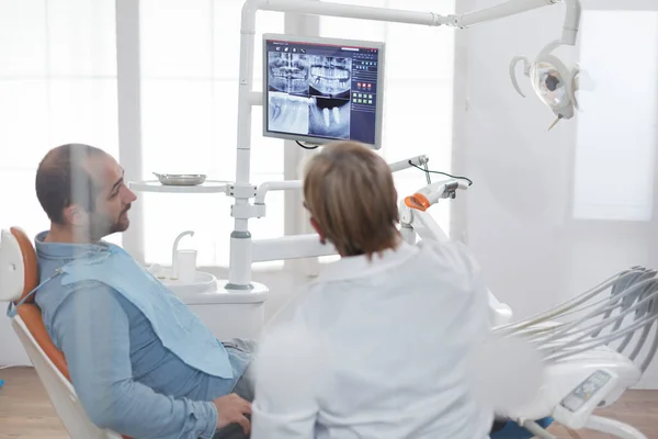 Paziente con mal di denti seduto sulla sedia dentale guardando la radiografia dei denti — Foto Stock