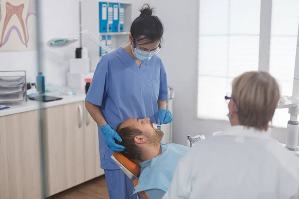 Медсестра-стоматолог делает анестезию ватным тампоном. — стоковое фото