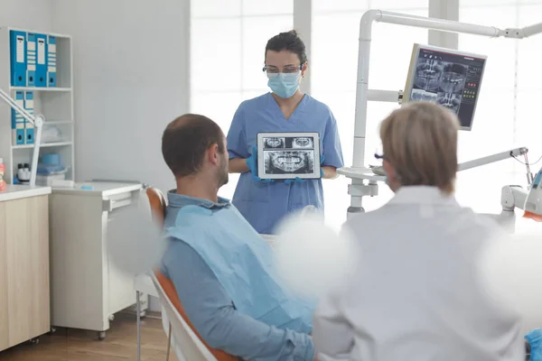 Specialista ortodontista infermiera indossa maschera che mostra radiografia dei denti — Foto Stock