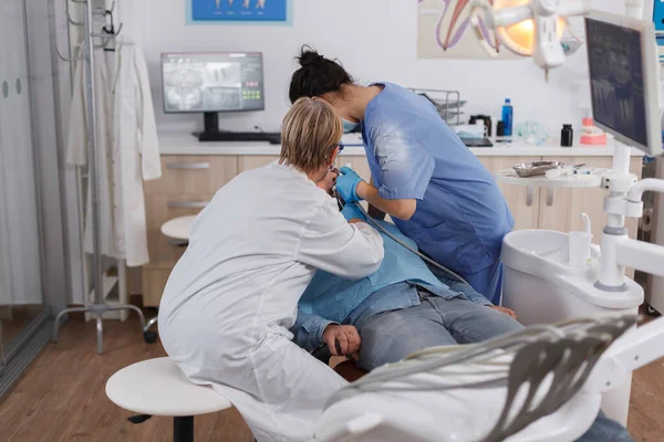 Команда врачей-стоматологов оперирует пациента кариесом — стоковое фото