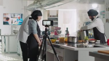 Kadın aşçı TV programında yemek pişirme videosu kaydediyor.