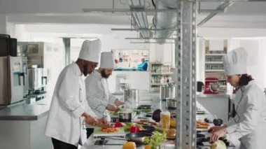 Afro-Amerikalı aşçı dolma biber kesip tavaya biber ekliyor.