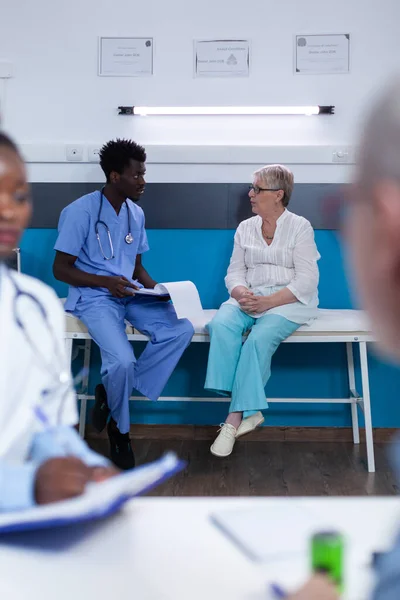 Sjuksköterska diskuterar med sjuka pensionerade patienter i läkarkabinettet — Stockfoto