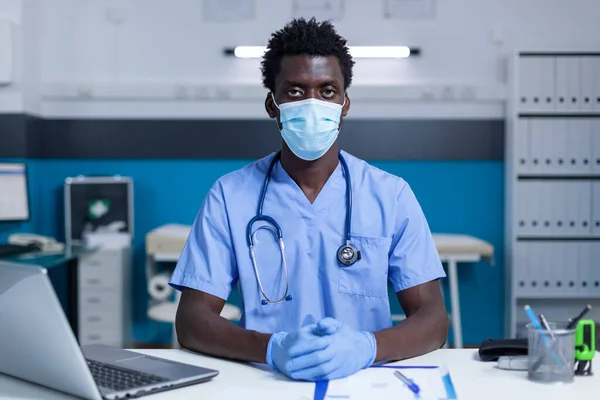 Personal médico del hospital sentado en la mesa en el gabinete de la clínica mientras usa guantes quirúrgicos —  Fotos de Stock