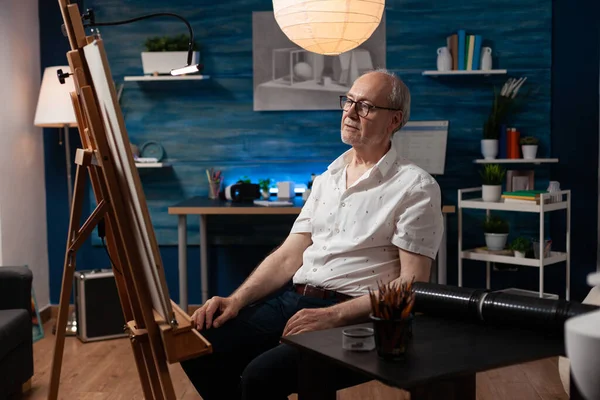 Artiste à la retraite fatigué se reposant en regardant des œuvres d'art admirant le résultat du travail dans la soirée — Photo