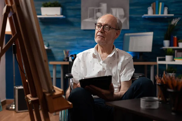 Older man sitting in wheelchair holding digital tablet computer looking at vase sketch drawing — Stock Photo, Image