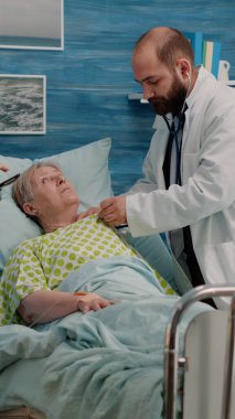 Doktor hasta üzerinde steteskop kullanarak kalp atışı kontrolü yapıyor.