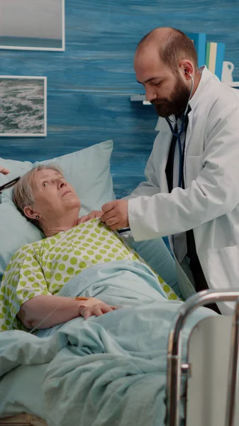 Doktor hasta üzerinde steteskop kullanarak kalp atışı kontrolü yapıyor.