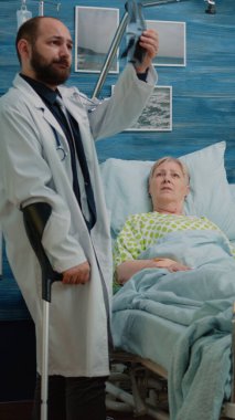 Hemşire yaşlı hastaya muayene için röntgen taraması yapıyor.