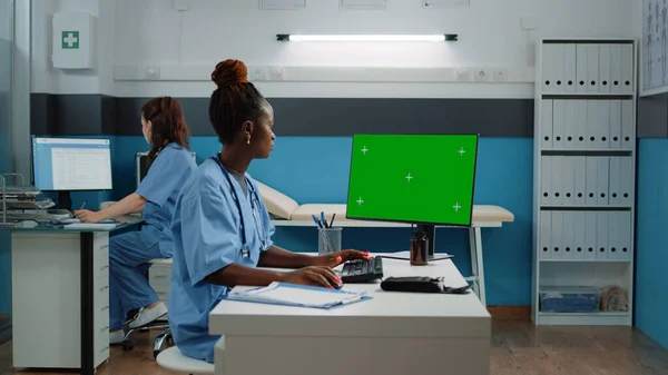 Assistant médical utilisant un ordinateur avec écran vert horizontal — Photo