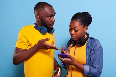 Şok olmuş adam ve kadın cep telefonu ekranını işaret ediyor