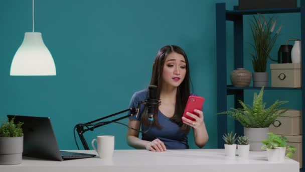 Asiatischer Vlogger liest Kommentare mit Handy vor der Kamera — Stockvideo