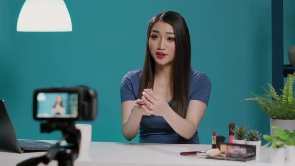 Asian influencer reviewing lipstick product on vlogging camera — ストック動画