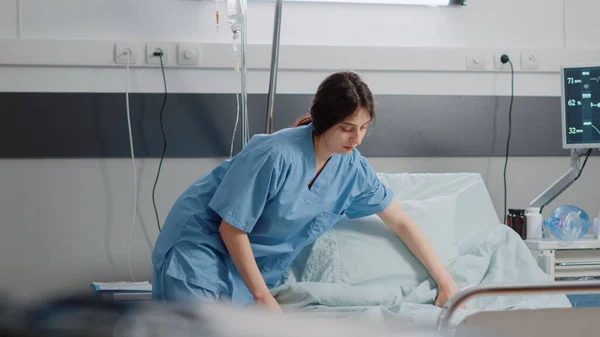Женщина, работающая медсестрой, готовит кровать в палате больницы — стоковое фото