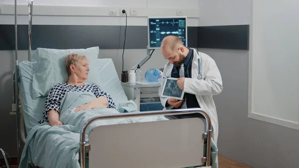 Médico apuntando a la pantalla de la tableta con radiografía para mujer enferma —  Fotos de Stock