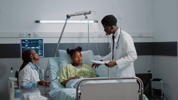 Afro-Amerikaanse man en vrouw consulting patiënt in bed — Stockfoto
