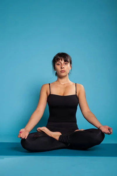 Personal trainer seduto sul tappetino yoga in posizione loto — Foto Stock